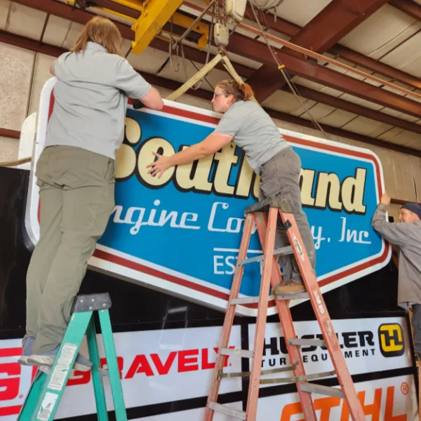 Unisignco crew mounting a Southland Engine Company sign inside an equipment dealership