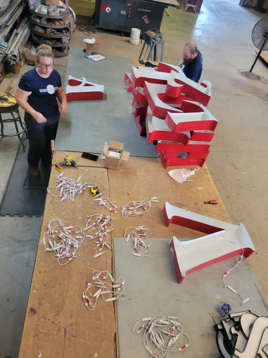 Unisignco fabricators assembling red and white channel letter shells with LED modules in the shop